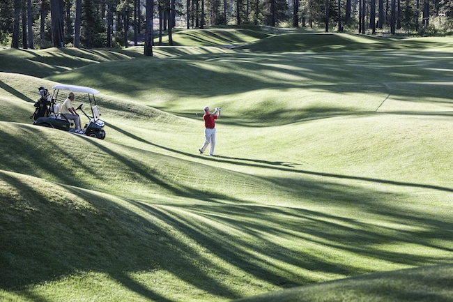 Senior golfer hitting a second shot from the fairway of a golf course.